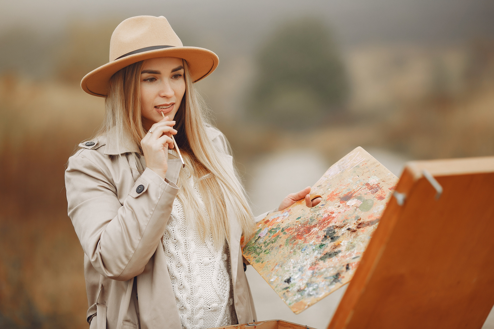 Young woman painting on easel outside